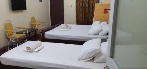 two beds in a room with chairs and a mirror at Cool Martin Family Hotel and Resort in Bacoor