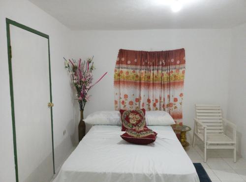 1 dormitorio con 1 cama con ventana y silla en Cozy Family Inn en Port Antonio
