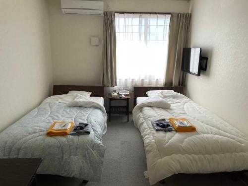 Dos camas en una habitación de hotel con toallas. en Yasuragino Yado -Iyashino Yu- en Kitakami
