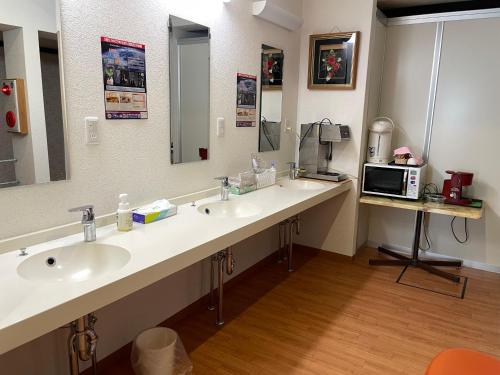 a bathroom with three sinks and a counter with a microwave at Yasuragino Yado -Iyashino Yu- in Kitakami