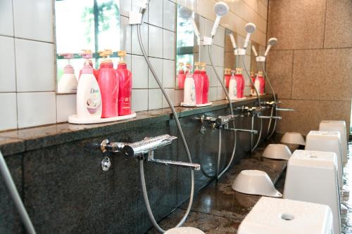 a bathroom with a shower with red bottles on the wall at ＹＵＦＵＩＮ　ＦＬＯＲＡＬ　ＶＩＬＬＡＧＥ　ＨＯＴＥＬ in Yufu