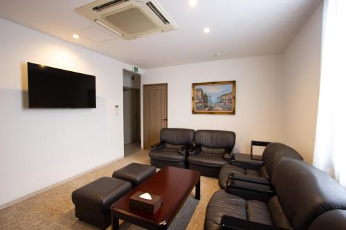 a living room with leather furniture and a flat screen tv at HIRO BUILDING Apartment Stay in Fukuoka