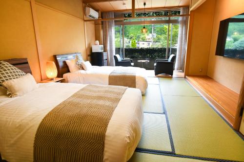 a hotel room with two beds and a window at ＹＵＦＵＩＮ　ＦＬＯＲＡＬ　ＶＩＬＬＡＧＥ　ＨＯＴＥＬ in Yufu