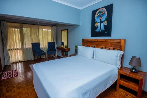 Nyumbani Palace Arusha في أروشا: غرفة نوم بسرير ابيض كبير وجدران زرقاء