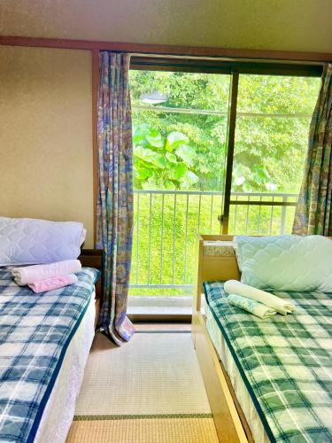 a bedroom with two beds and a window with a balcony at Shirahama in Miyazaki