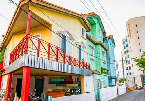 un bâtiment coloré avec un panneau devant lui dans l'établissement PyoLi Guesthouse, à Seogwipo