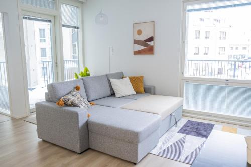 uma sala de estar com um sofá cinzento num quarto com janelas em Snowflake Suites II em Rovaniemi