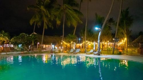 a swimming pool at night with palm trees and lights at MUINE SUN & SEA BEACH ( BOUTIQUE RESORT & GLAMPING) in Mui Ne