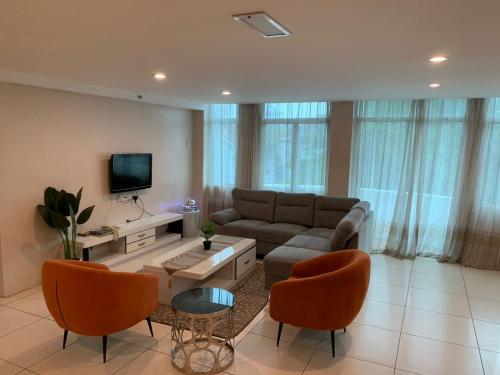 Simfoni Resort Langkawi في كواه: غرفة معيشة مع أريكة وكراسي وتلفزيون