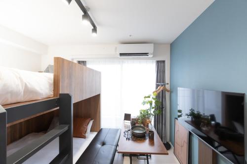 Un dormitorio con una cama, una mesa y un televisor. en Primavera Namba, en Osaka
