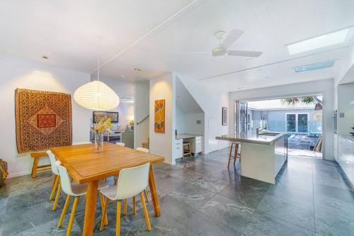 a kitchen and dining room with a wooden table and chairs at Fuller Holidays - Adrift - Tallows Beachfront Suffolk Park in Suffolk Park
