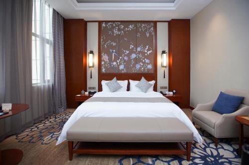 YunRay Hotel Shijiazhuang في هيبي: غرفة نوم بسرير ابيض كبير واريكة