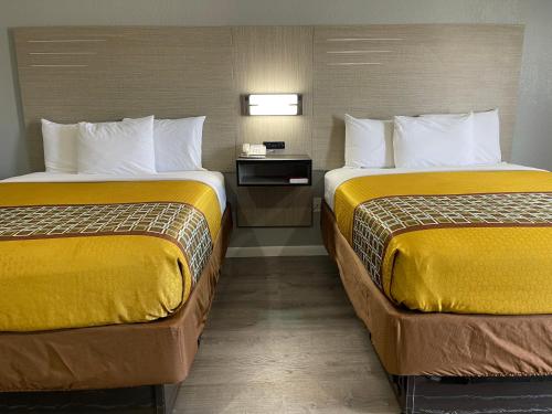 two beds in a hotel room with yellow covers at Copper Manor Motel in Silver City