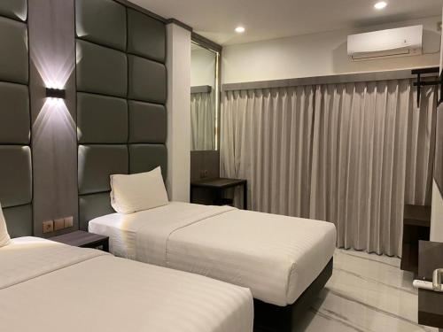 a hotel room with two beds and a mirror at panfila hotel in Kuta Lombok