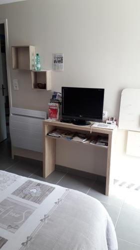 Zimmer mit einem TV auf einem Schreibtisch mit einem Bett in der Unterkunft Chambre d'hôtes Juline 