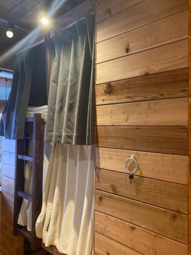 a bed in a room with a wooden wall at Surfer's Cafe& Hostel in Chatan
