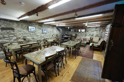 restauracja ze stołami i krzesłami oraz kamienną ścianą w obiekcie Villa Mestia Hotel w mieście Mestia