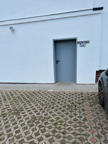 a white building with a blue door in a parking lot at Ferienwohnung Appartamento Da Vinci in Eisenach