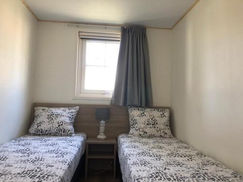 twee bedden in een kleine kamer met een raam bij Vakantiehuis voor 6 personen in Opheusden