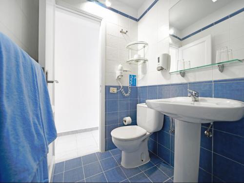 a blue and white bathroom with a toilet and a sink at Bungalows Vistaflor in Maspalomas