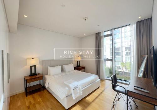 a bedroom with a bed and a desk and a television at Crystal Clear 1BR Apt in Blue Waters by Rich Stay in Dubai