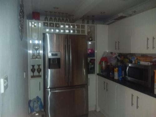 eine Küche mit einem Kühlschrank aus Edelstahl und weißen Schränken in der Unterkunft Opal Art House in Coober Pedy