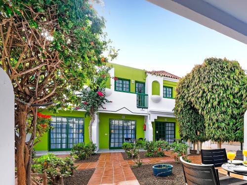 a green and white building with a patio and trees at Bungalows Vistaflor in Maspalomas