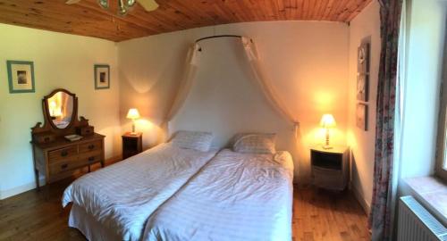 um quarto com uma cama branca e 2 candeeiros em La Roderie em Abjat