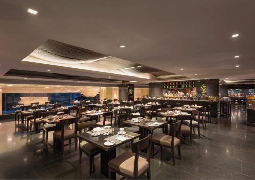 um restaurante com mesas e cadeiras e um bar em Crowne Plaza Kochi, an IHG Hotel em Cochin