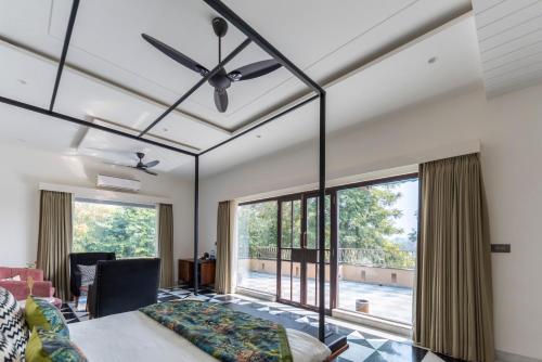 a dining room with a ceiling fan and large windows at Vanaashrya Resort and Spa Sariska in Tehla