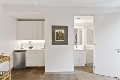 a kitchen with white cabinets and a mirror at Top of the town in Bangalow
