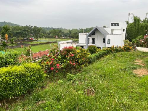 a garden with flowers in front of a white building at Yahiya in Sylhet