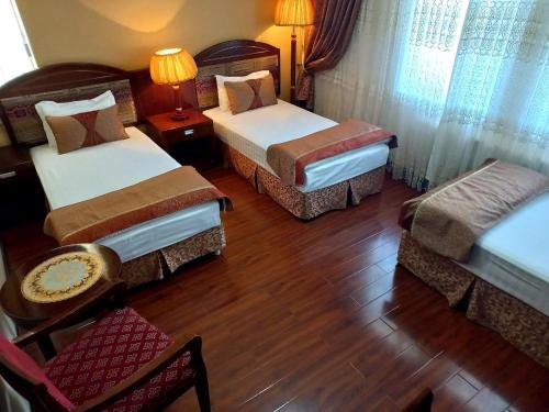 ein Hotelzimmer mit 3 Betten sowie einem Tisch und Stühlen in der Unterkunft Kamelot in Buxoro