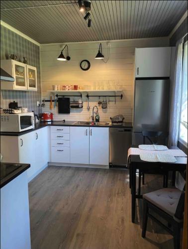 a kitchen with white cabinets and a black refrigerator at Hus nära Hallstaberget in Sollefteå