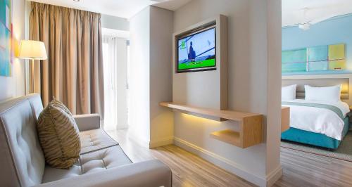 a hotel room with a bed and a tv at Holiday Inn Mauritius Mon Trésor by IHG in Blue Bay