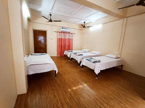 a row of beds in a room with wood floors at Nain Guest House in Ujjain