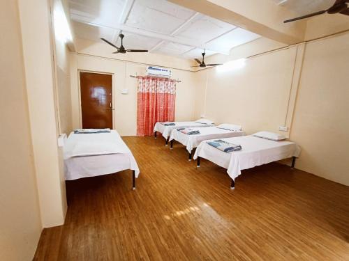 uma fila de camas num quarto com pisos de madeira em Nain Guest House em Ujjain