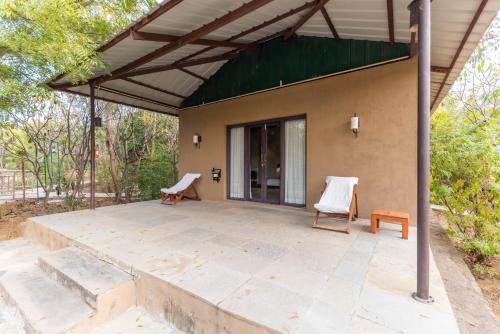 a patio with two chairs and a building at Vanaashrya Resort and Spa Sariska in Tehla