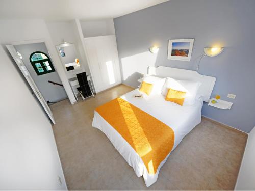 a bedroom with a large white bed with an orange blanket at Bungalows Vistaflor in Maspalomas