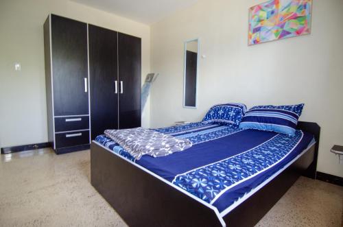 a bedroom with a bed with blue sheets and a cabinet at Blue Apartments in Willemstad