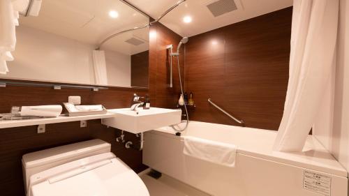 a bathroom with a toilet and a sink and a tub at Kobe Hotel Juraku in Kobe