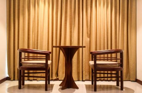 two chairs and a table in front of a curtain at Classic Sarovar Portico Trivandrum in Trivandrum