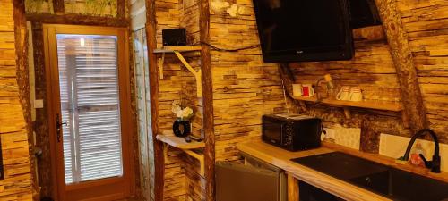 a kitchen with a wooden wall with a microwave and a television at La cabane des amoureux in Sarlat-la-Canéda