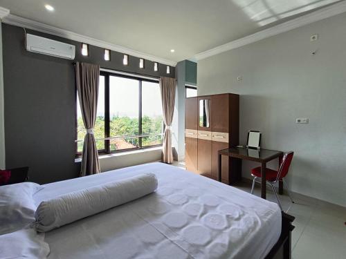 a bedroom with a bed and a desk and a window at RedDoorz @ Green Homestay Syariah Baubau in Baubau