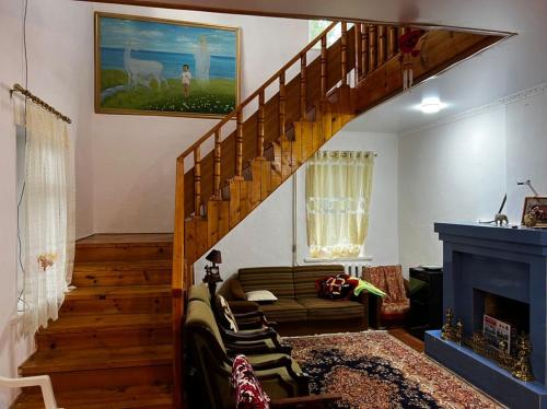 a living room with a staircase with a couch and a fireplace at Гостевой дом “Kyzyl Alma” (Red Apple) in Chon-Dzhargylchak