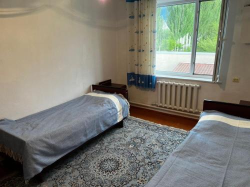 a bedroom with two beds and a window at Гостевой дом “Kyzyl Alma” (Red Apple) in Chon-Dzhargylchak