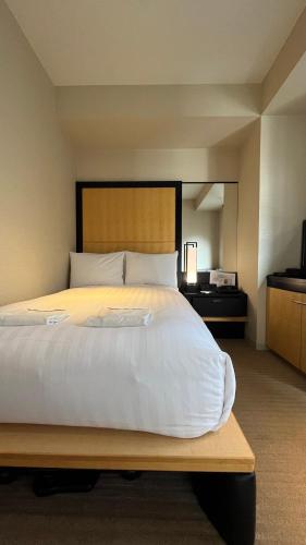 a bedroom with a large white bed with a desk at KOKO HOTEL Premier Kanazawa Korinbo in Kanazawa