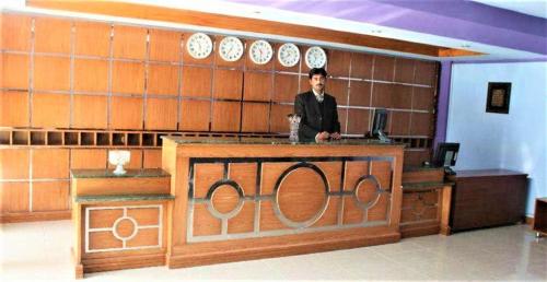 a man standing behind a counter in a room at The Ballagio Inn in Islamabad
