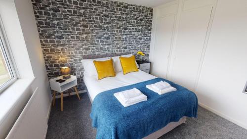 um quarto com uma cama com almofadas amarelas e uma parede de tijolos em Flexley House Workstays UK em Middlesbrough
