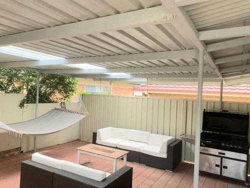 a patio with a couch and a hammock and awning at Cottage 3mn walk CBD/Marina. Wifi,AC, pet-friendly in Nelson Bay